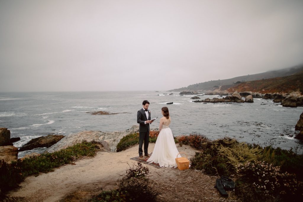 A couple getting married on the cliffs of Big Sur. The groom is reading his vows in a private elopement ceremony.