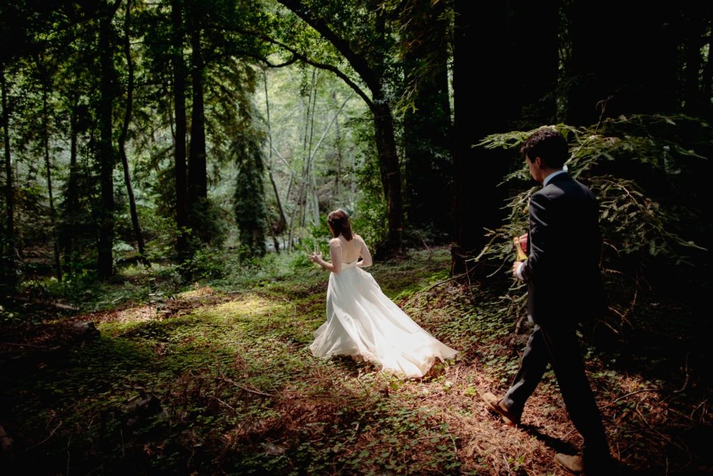 A couple waling through the redwood forest of Big Sur, wearing their elopement attire. 