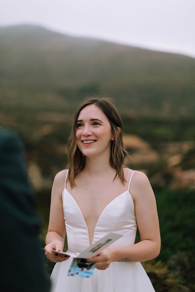 bride reading letters from family on her wedding day on cliffs of big sur california
