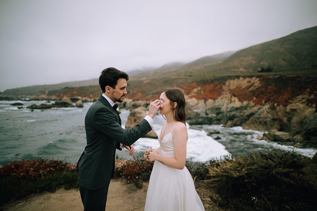 Groom wiping away tears of Bride at Garrapata State Park