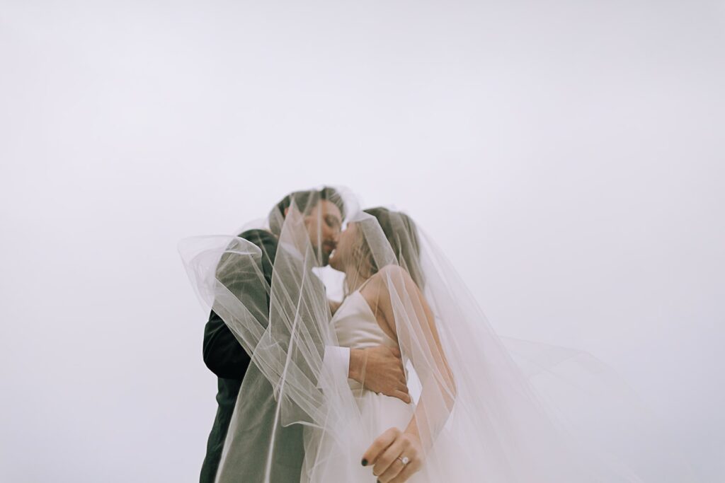 Couple kissing under her veil in Big Sur California