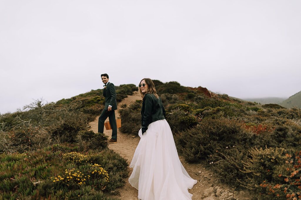 Bride in leather jacket hiking on wedding day Big Sur