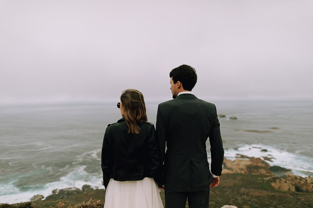 Bride and Groom looking at ocean on the cliffs of Big Sur