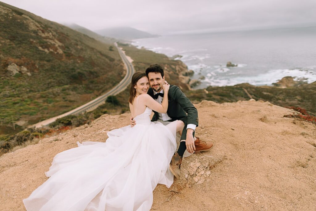 Couple on top of the cliffs of Big Sur in their wedding outfits