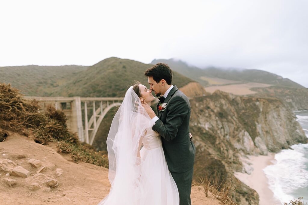 eloping couple kissing in front of Bixby Bridge in Big Sur
